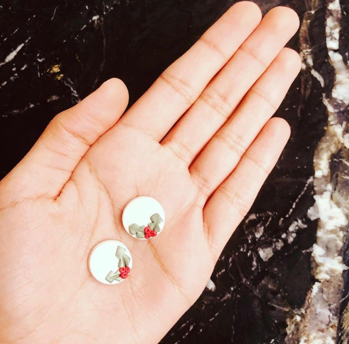 Holly Berry Studs: small white studs with holly leaves and red berries, held in a hand
