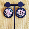 Midnight Rose Drops: black round earrings with blush roses on a stand