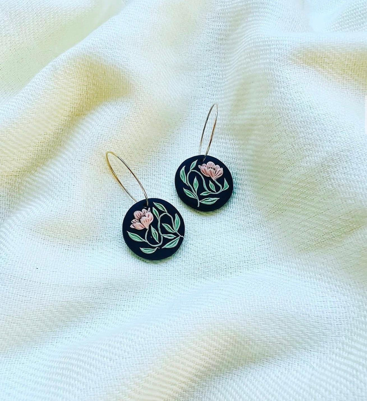 Noir Bloom Hoops: black round charms with a blush flower on gold hoops