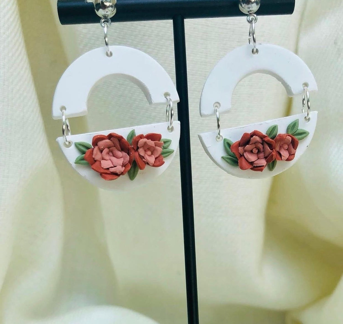 Rose Arch Earrings: white arch and half-moon earrings with red roses on a stand