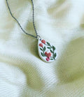 Rosebird Pendant: white teardrop pendant with a coral bird and red roses