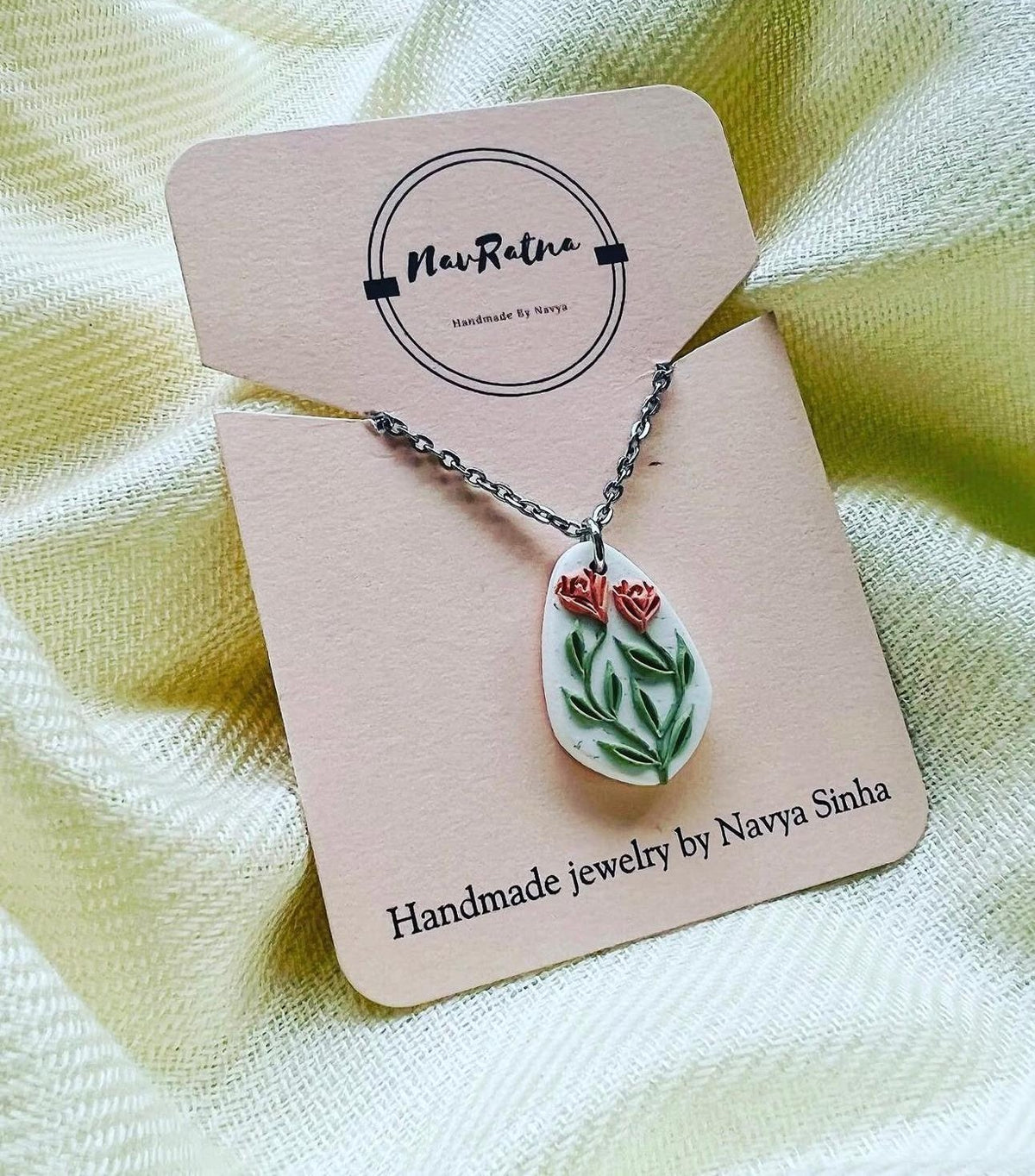 Twin Rose Pendant: white oval pendant with two coral roses on a NavRatna card