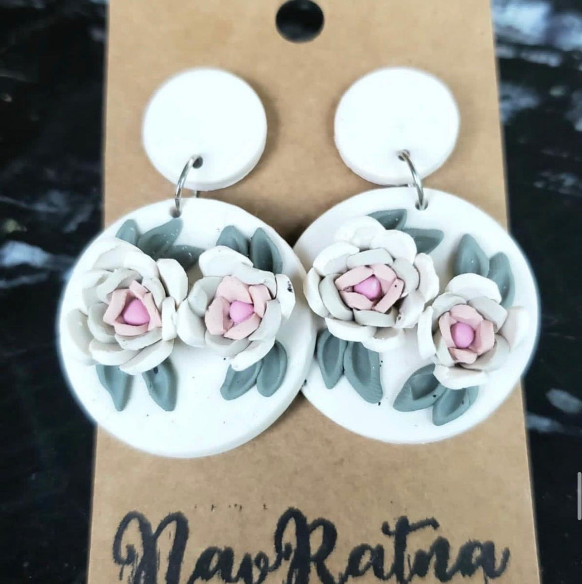 White Camellia Drops: white round earrings with pink-centered camellias on a NavRatna card